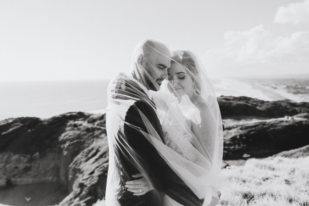 Bride and groom under the veil at Muriwai