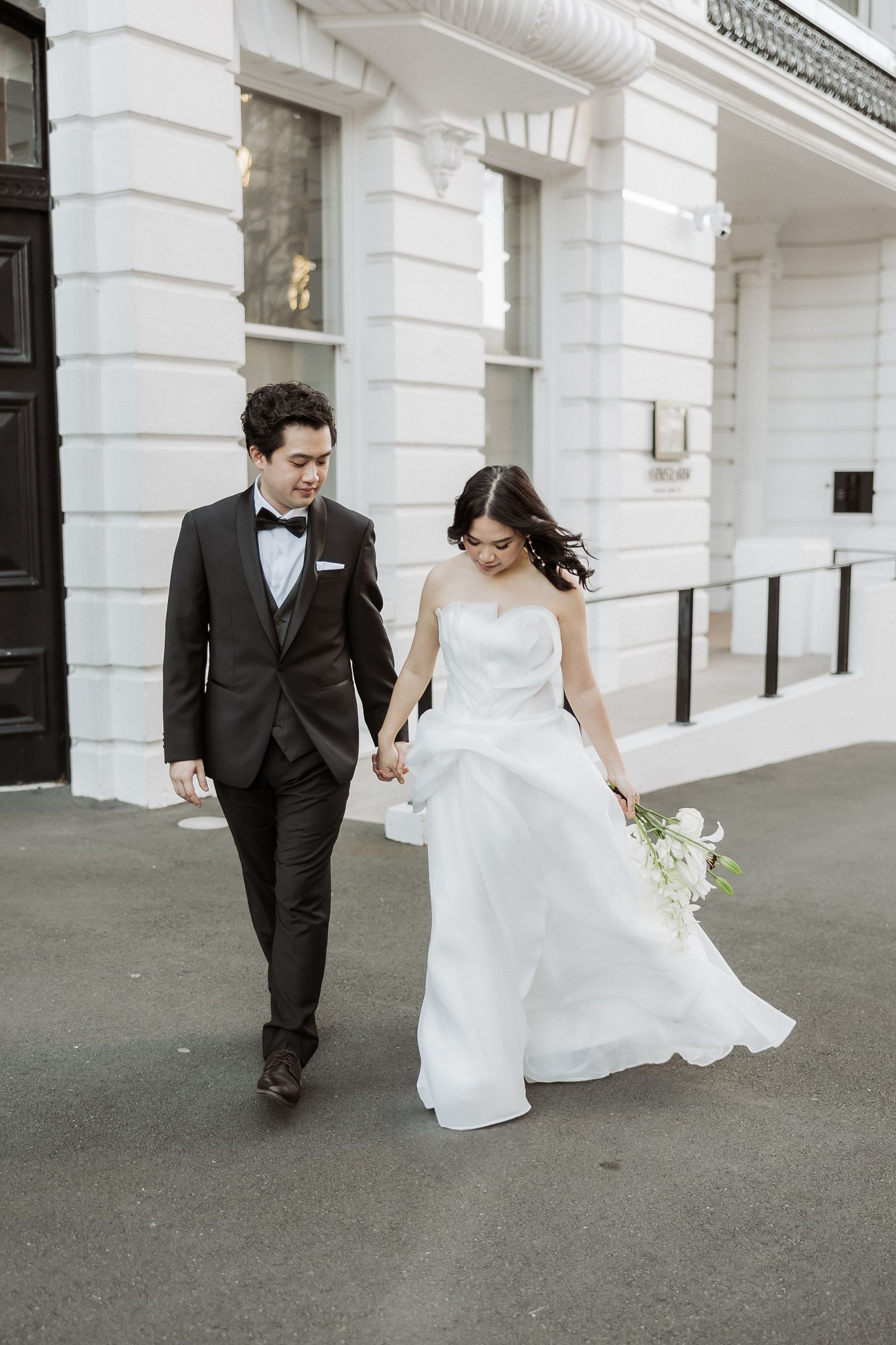 Bride and groom walking past a white heritage building in the Auckland CBD