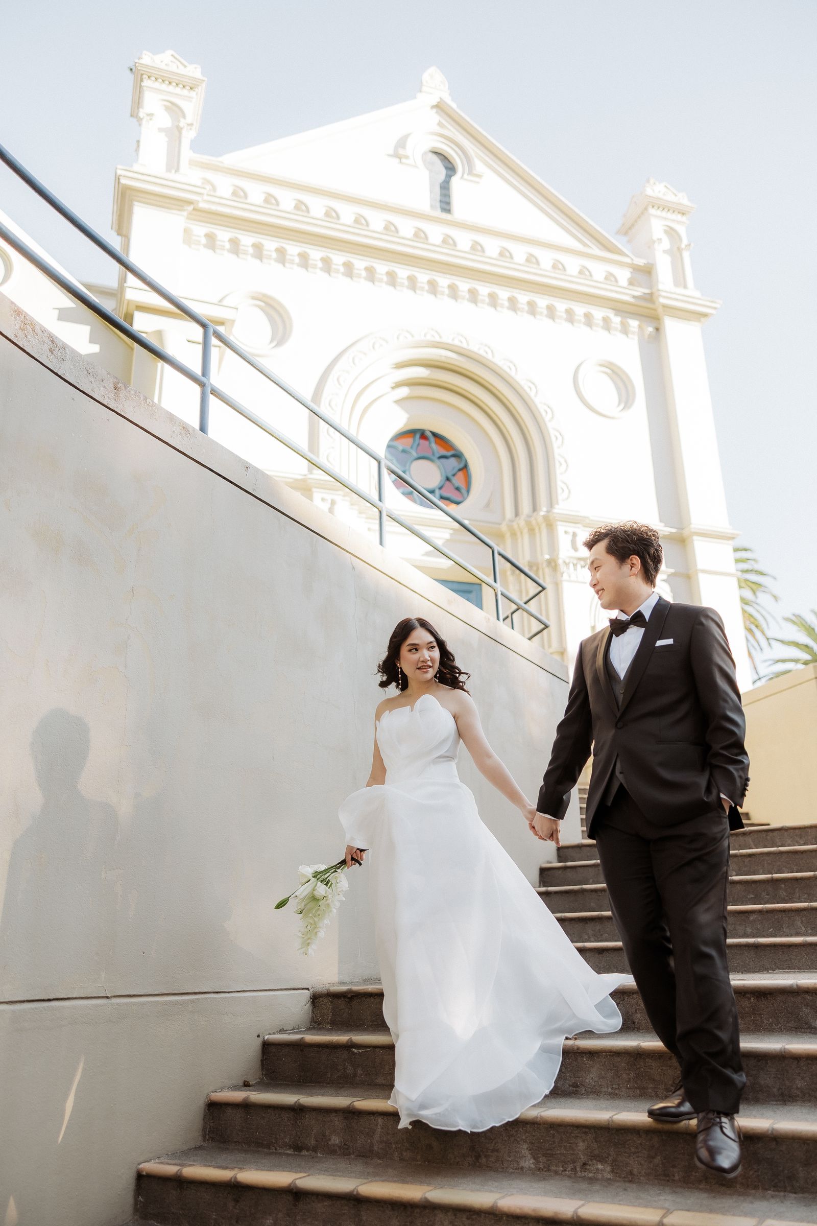 Bride and groom walking down church steps in Auckland city