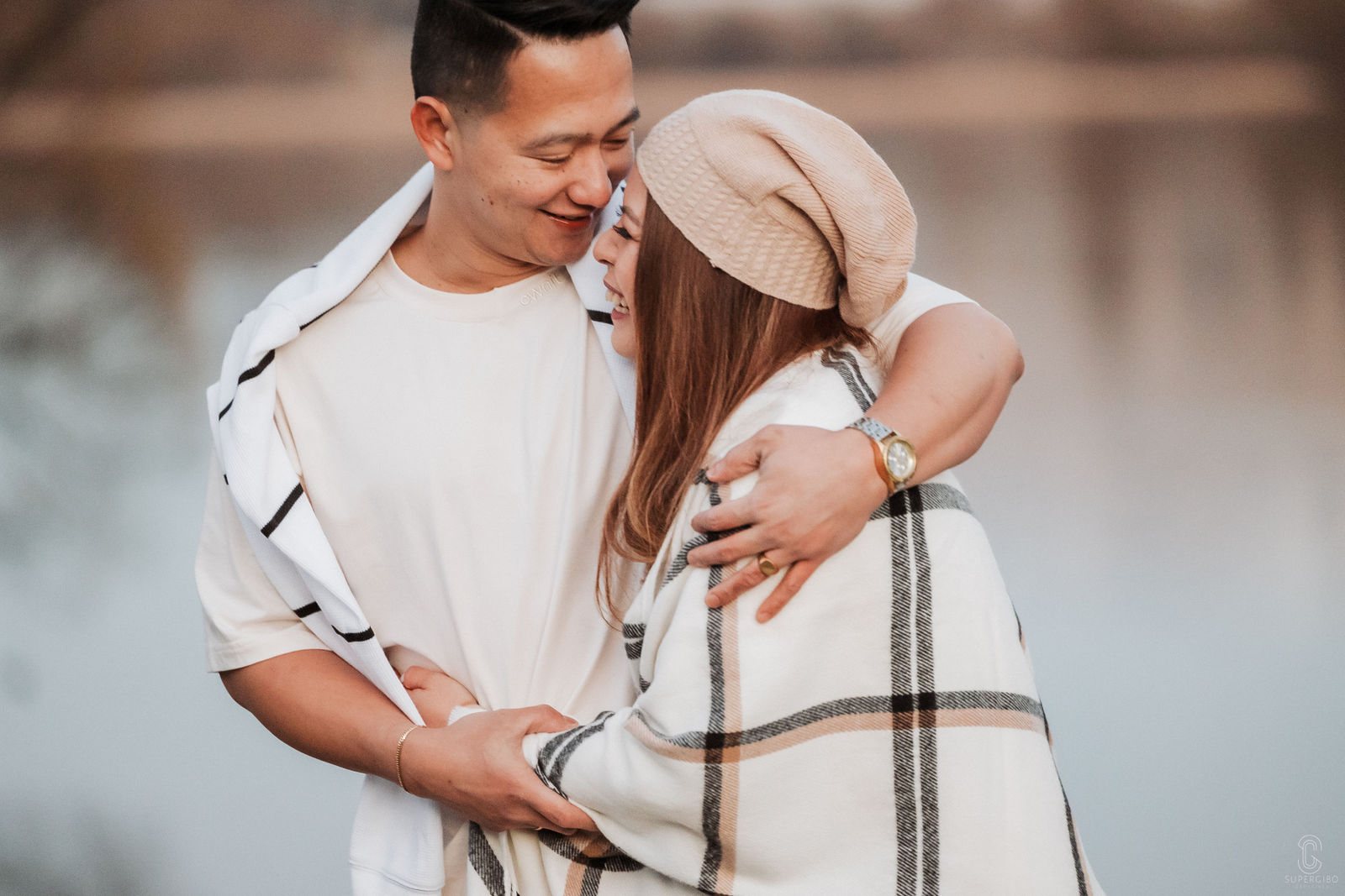 Couple wrapped in a blanket laughing on an engagement session near Queenstown