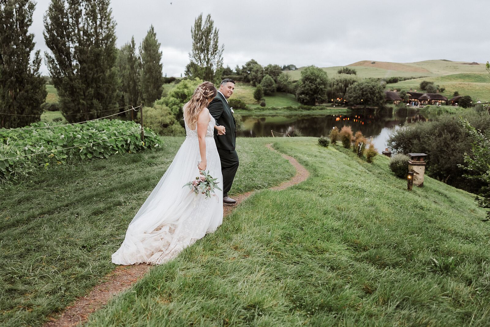 Bride and groom on the hillside path at Hobbiton at dusk