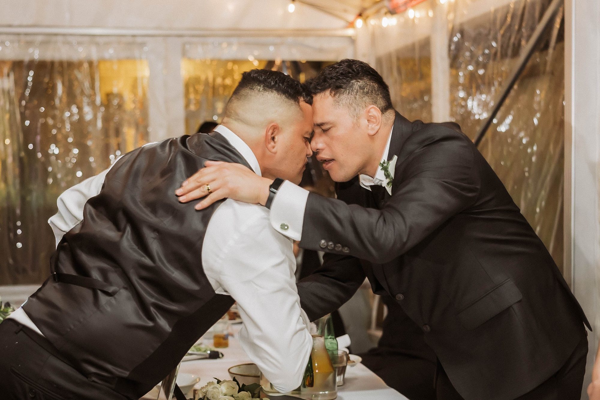 Two men sharing a hongi at a Māori wedding reception in Auckland
