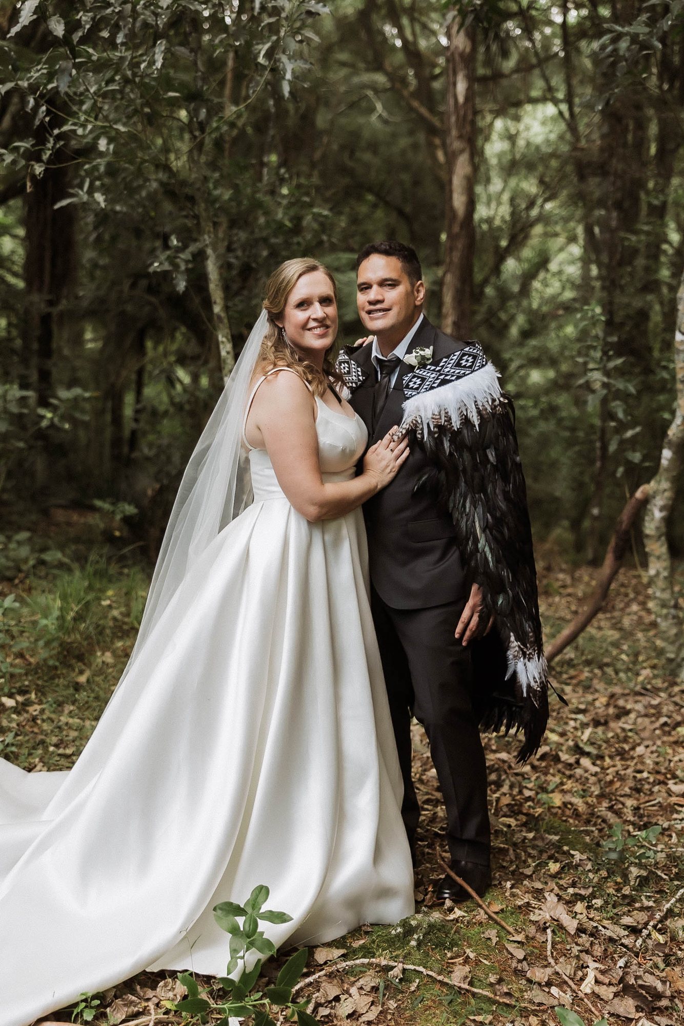 Bride and groom in the bush, the groom wearing a korowai, at an Auckland Māori wedding