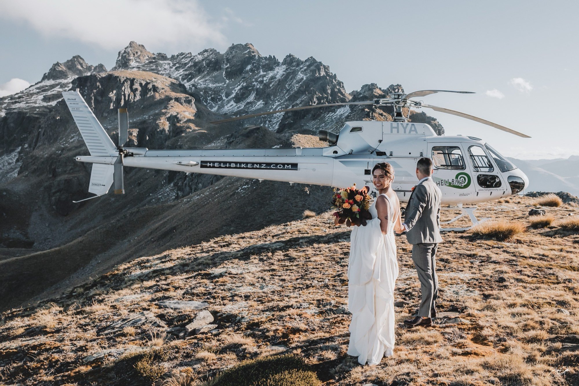 Bride and groom walking to a helicopter on a mountain ridge at a Queenstown elopement