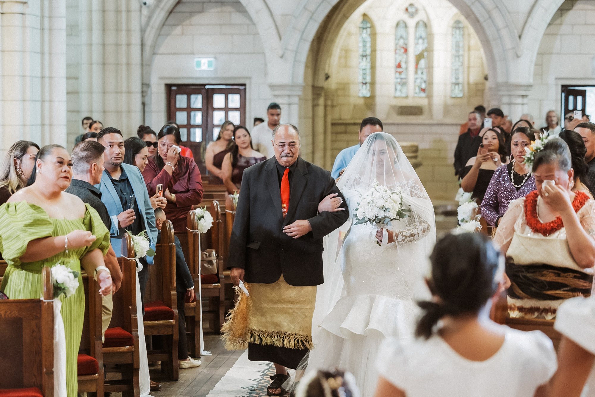 Father in a ta’ovala walking his daughter down the aisle at a Tongan wedding in Auckland