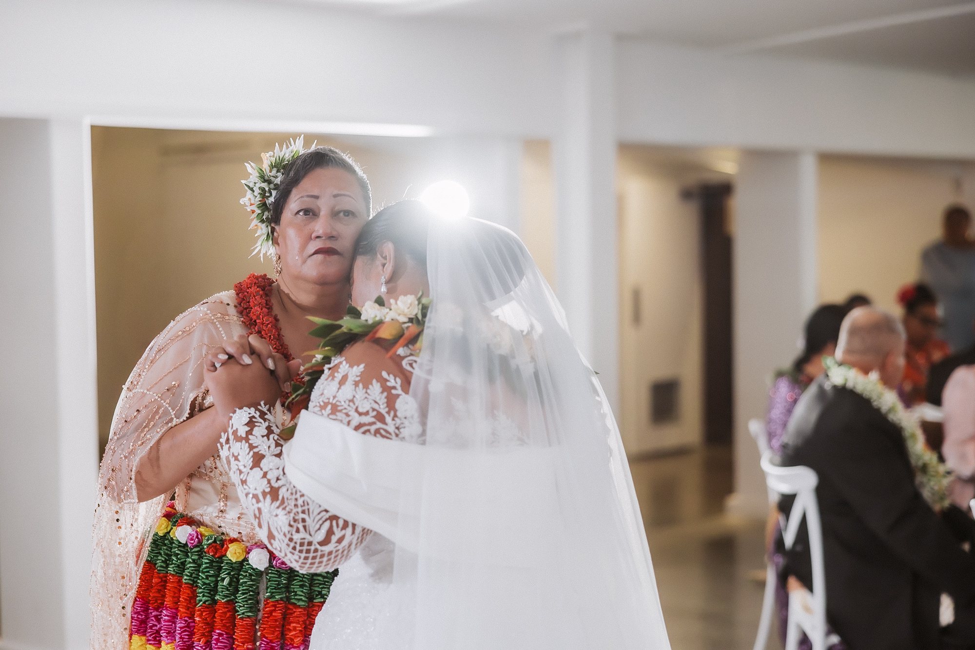 Bride’s mother in a kahoa holding her daughter after a Tongan wedding ceremony in Auckland